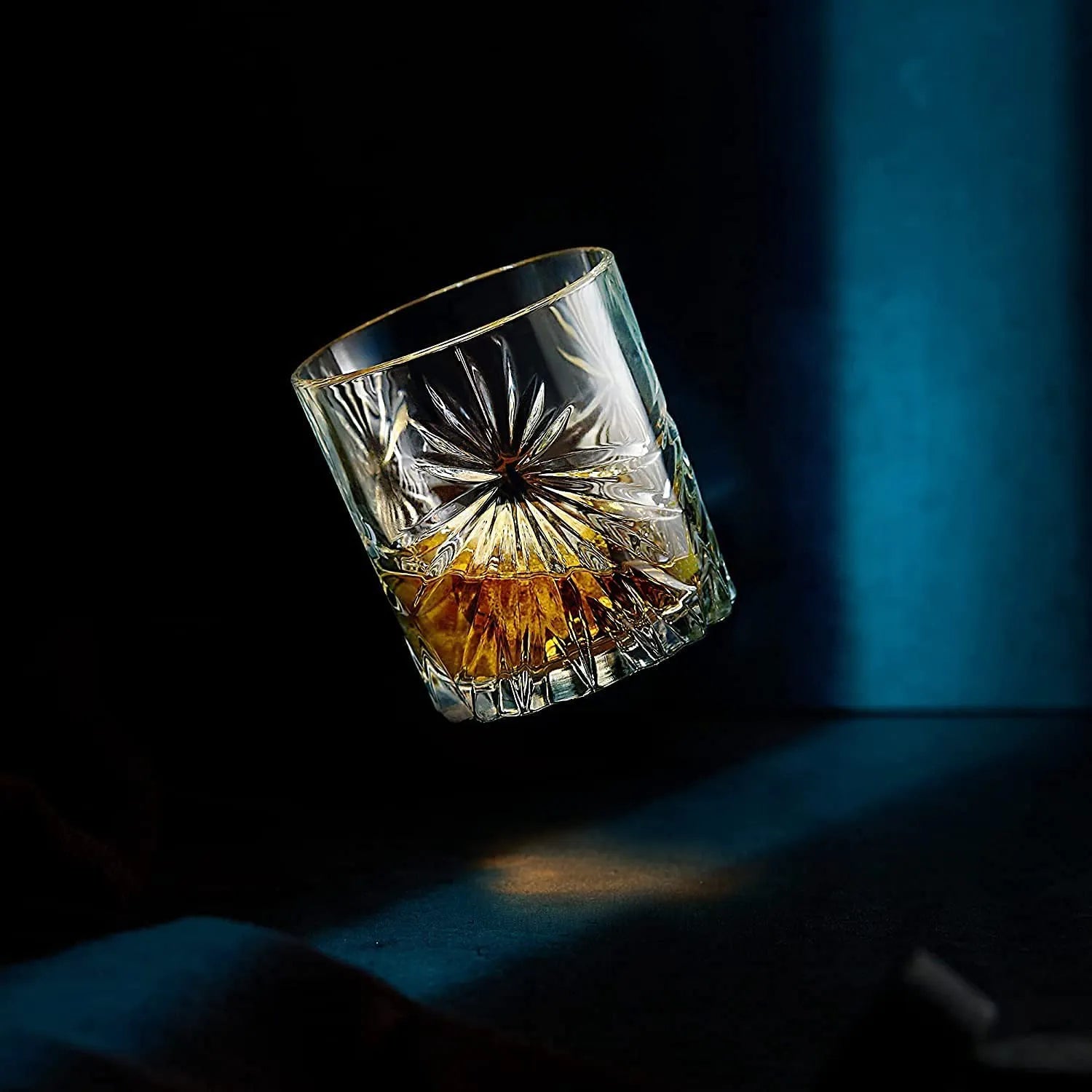 Soleil Whiskyglas vor blauem Hintergrund, fällt gerade zu Boden