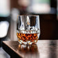 Iconic Whiskyglas mit Whisky gefüllt steht an der Kante eines Tisches