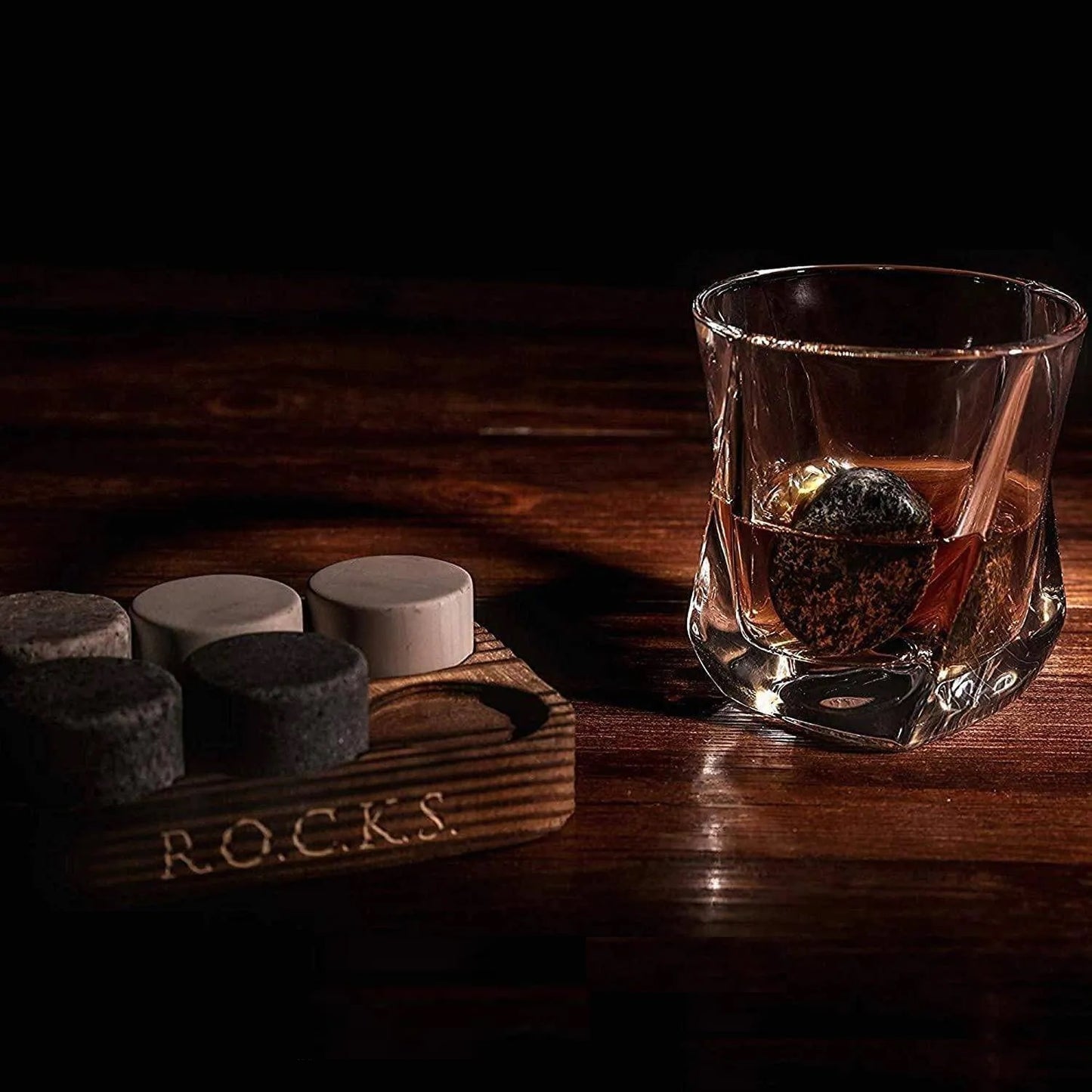 Twist Whiskyglas mit Whisky gefüllt und einem Kühlstein im Glas neben den restlichen Steinen wird von Licht angestrahlt